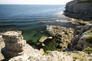 A rocky quarry overlooks the sea. Green moss grows on the rocks.