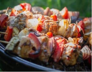 Five skewer on a barbecue, containing red peppers, onions and pork.
