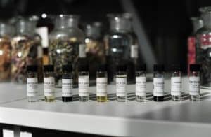 A row of 10 small perfume sample bottles in front of various jars of herbs and dried flowers at Keyneston Mill.