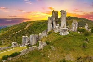 Corfe castle against a orange, yellow and purple sunset