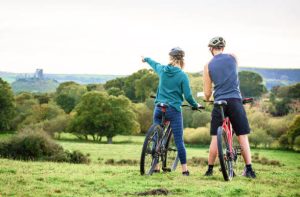 Man and woman on bikes on green grassy hill
