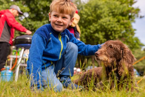 Young boy petting his dog when camping